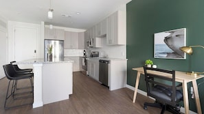 A modern kitchen with white cabinetry, stainless appliances, and a central island. - Landing | Stunning 1BD, Gym, Yoga Studio (Sarasota)