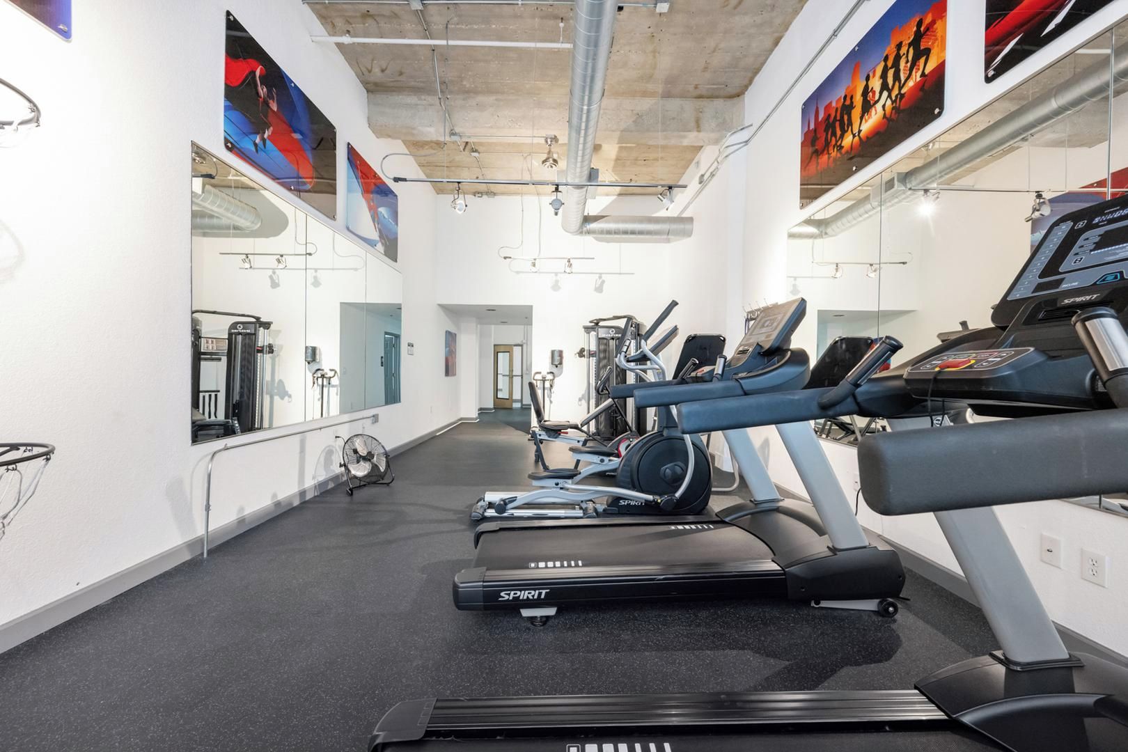 A gym with treadmills, exercise bikes, and mirrors on the walls.