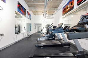 Ein Fitnessstudio mit Laufbändern, Ergometer und Spiegeln an den Wänden.