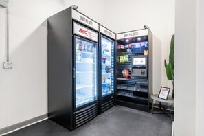 Ein Automatenbereich mit zwei Kühlgeräten, auf denen 'UNITY LOFTS' steht, und einem Schild der 'ARC Allied Refreshment Company'.
