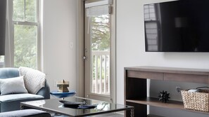 A modern living room with a sofa, coffee table, fireplace, and a flat-screen TV mounted on the wall. - Landing | Amazing 1BD, Gym (Gainesville)