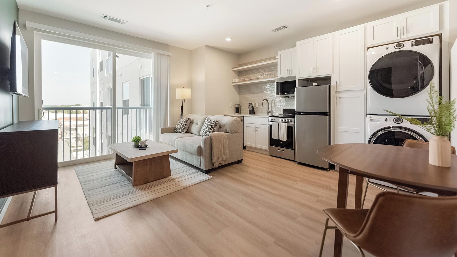 Un appartement moderne doté d’une cuisine, d’un coin repas et d’un balcon avec vue.