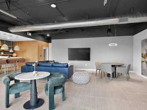 A modern interior with a sectional sofa, round tables, and a flat-screen TV.