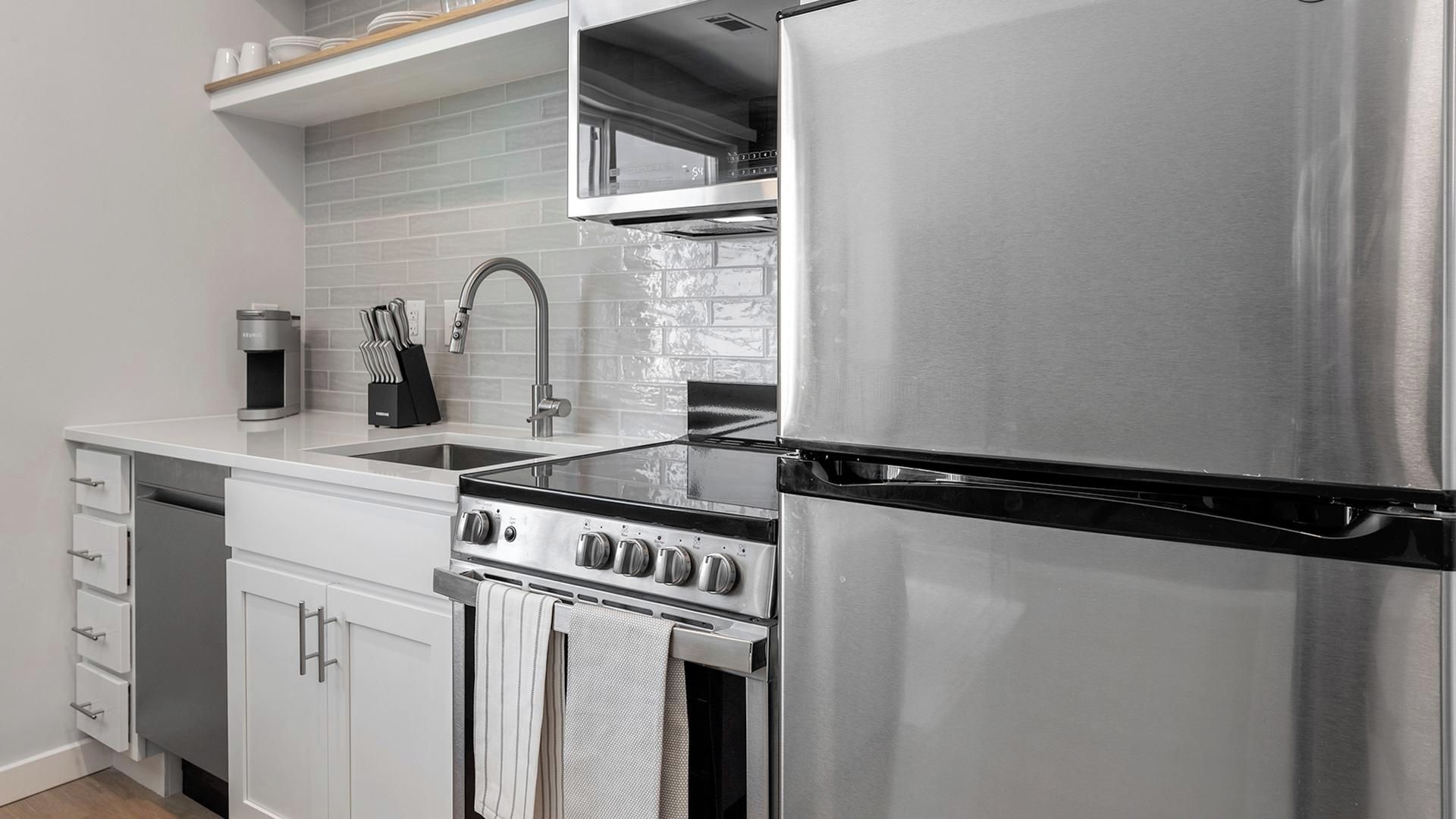 Una cocina moderna con electrodomésticos de acero inoxidable, horno empotrado y un lavamanos.