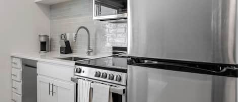 Una cocina moderna con electrodomésticos de acero inoxidable, horno empotrado y un lavamanos.
