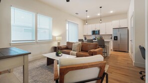 Uma sala de estar moderna com sofá, mesa de centro e um espaço de jantar com mesa e cadeiras.