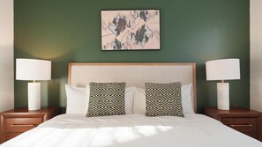 Ein Hotelzimmer mit einem Bett, zwei Nachttischen, zwei Lampen und einem Wandbild.