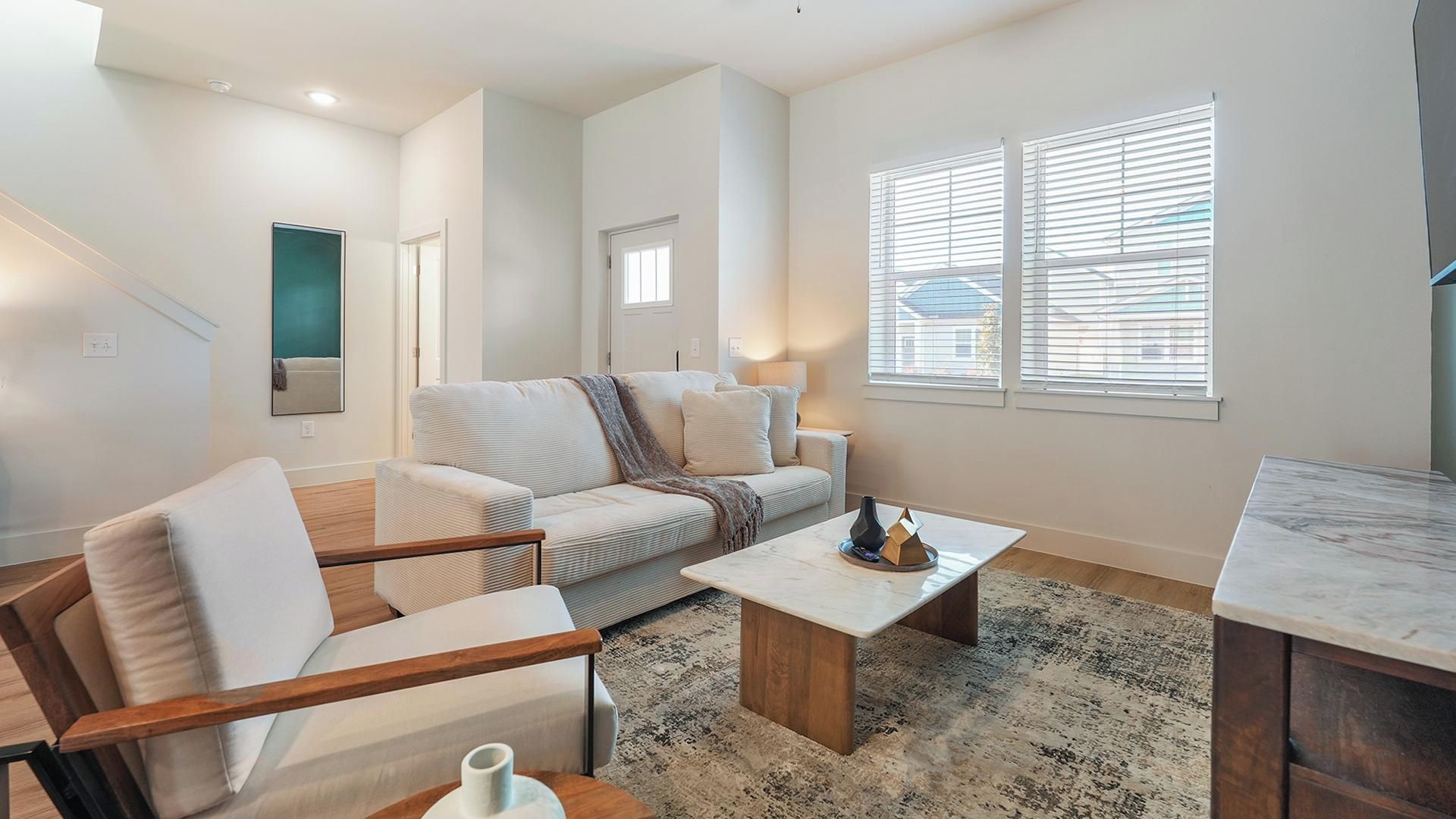 A modern living room with a sofa, coffee table, and a dining area.