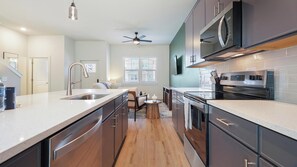 A modern kitchen with a large island, stainless steel appliances, and a ceiling fan. - Landing | Stunning 2BD, Gym (Palmetto)