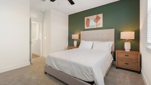 Una camera da letto con un letto, due comodini con lampade, un tavolino e una parete decorata con un quadro.