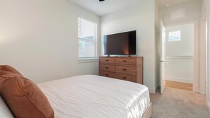 A bedroom with a bed, a dresser, a television on top, and a window with blinds. - Landing | Stunning 2BD, Gym (Palmetto)