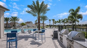 A poolside area with lounge chairs, a barbecue grill, and a trash can. - Landing | Amazing 2BD, Gym (Palmetto)