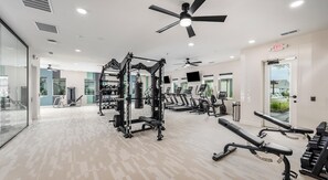 Ein Fitnessstudio mit Trainingsgeräten, Laufbändern und einem Deckenventilator.