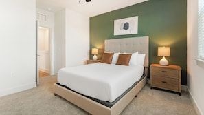 A bedroom with a large bed, two bedside tables with lamps, a wall-mounted artwork, and a door leading to another room. - Landing | Amazing 2BD, Gym (Palmetto)