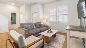 A modern living room with a sofa, coffee table, and TV stand. - Landing | Modern 2BD, Gym (Palmetto)