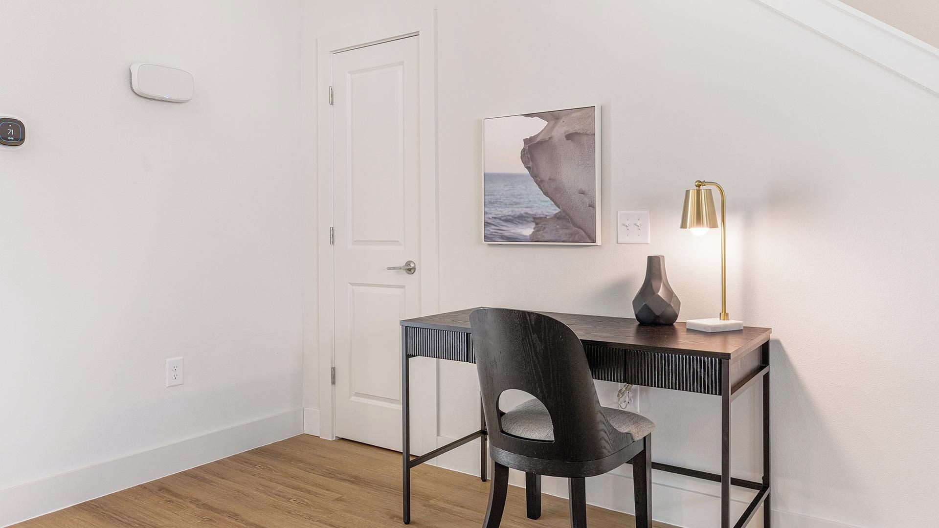 Una habitación con escritorio, silla y lámpara fijada a la pared.