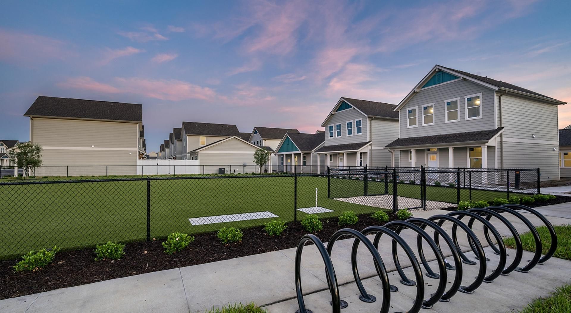 Un barrio residencial con casas, un patio cercado y una fila de aparcabicicletas.