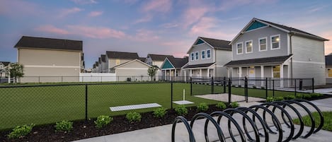 A residential area with houses, a fenced yard, and a row of bicycle racks.