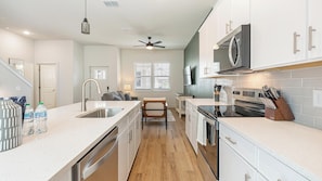 A modern kitchen with a central island, stainless steel appliances, and a microwave above the stove. - Landing | Modern 2BD, Gym (Palmetto)
