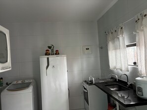 Een kleine keuken met een koelkast, een spoelbak en een fornuis.