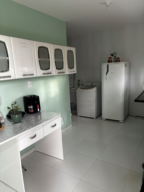 A kitchen with a white countertop, a sink, a refrigerator, and cabinets above the counter. - Praia do Francês: sun, sea, the lightness of being where the soul finds its balance. (Marechal Deodoro)