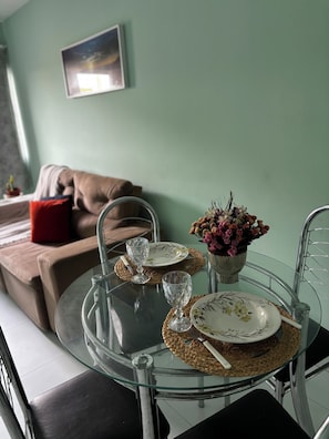 Een eetgedeelte met een glazen tafel, borden, bestek en een vaas met bloemen.