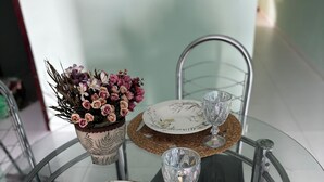 Uma mesa de vidro com dois pratos, uma tigela de vidro e um vaso com flores.