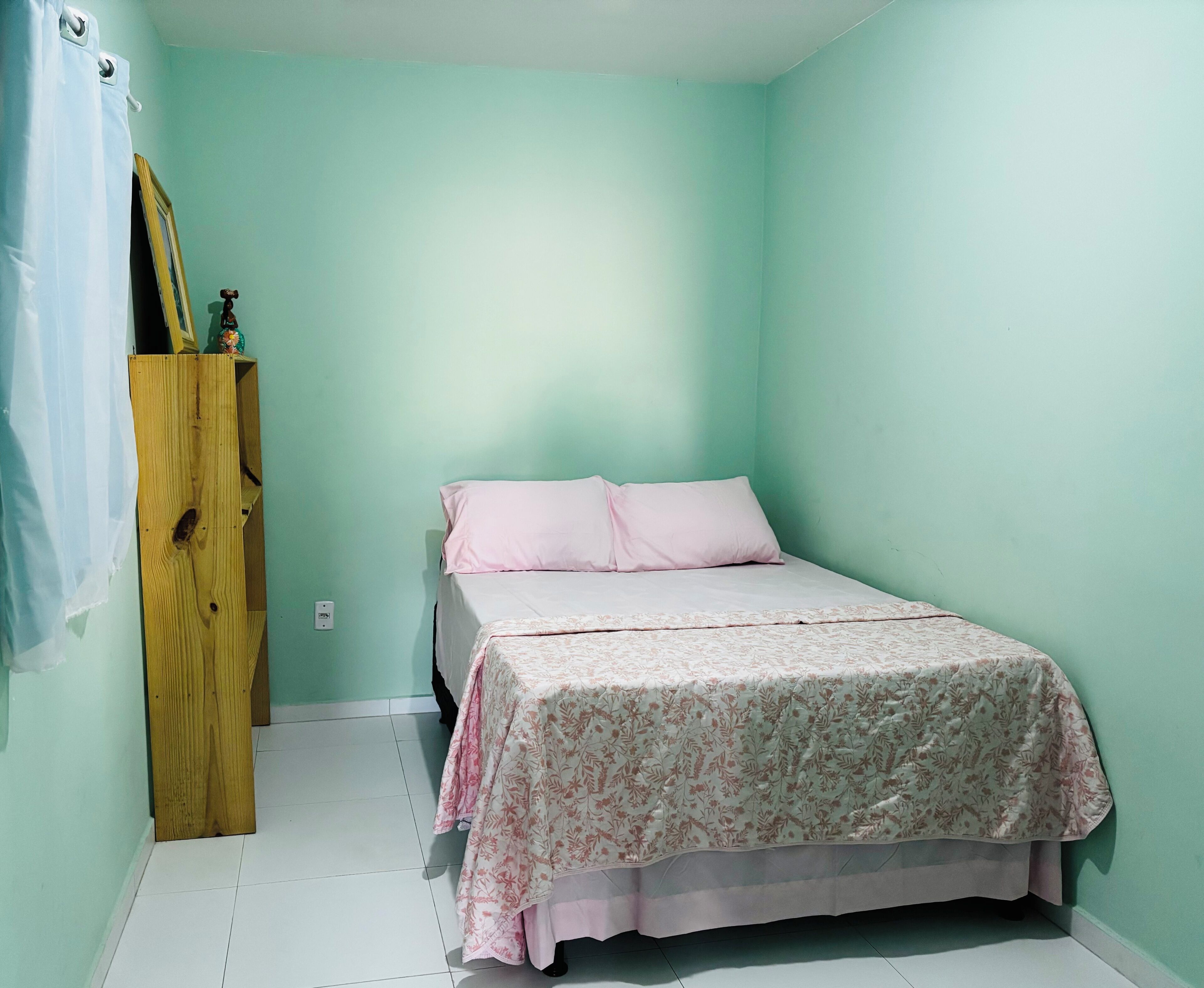 Una habitación con cama, un armario de madera y pared verde claro.