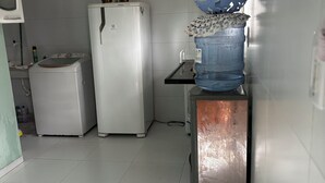 Cuina amb nevera, rentadora i dispensador d'aigua.