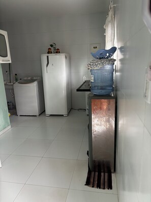 Een keuken met een koelkast, een wasmachine en een waterdispenser.