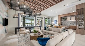 A spacious living area with a large sofa, a coffee table, and a dining area with a view of the outdoors. - Landing | Spectacular 2BD, Gym (Palmetto)
