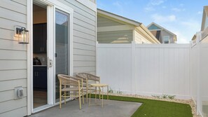 A residential property with a patio area featuring two wicker chairs and a small garden with artificial grass and gravel. - Landing | Spectacular 2BD, Gym (Palmetto)