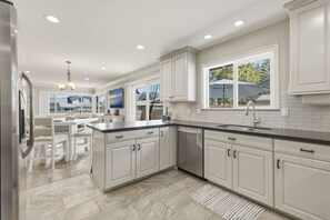 Una cocina moderna con armarios blancos, una isla central y un amplio ventanal con vistas al exterior.