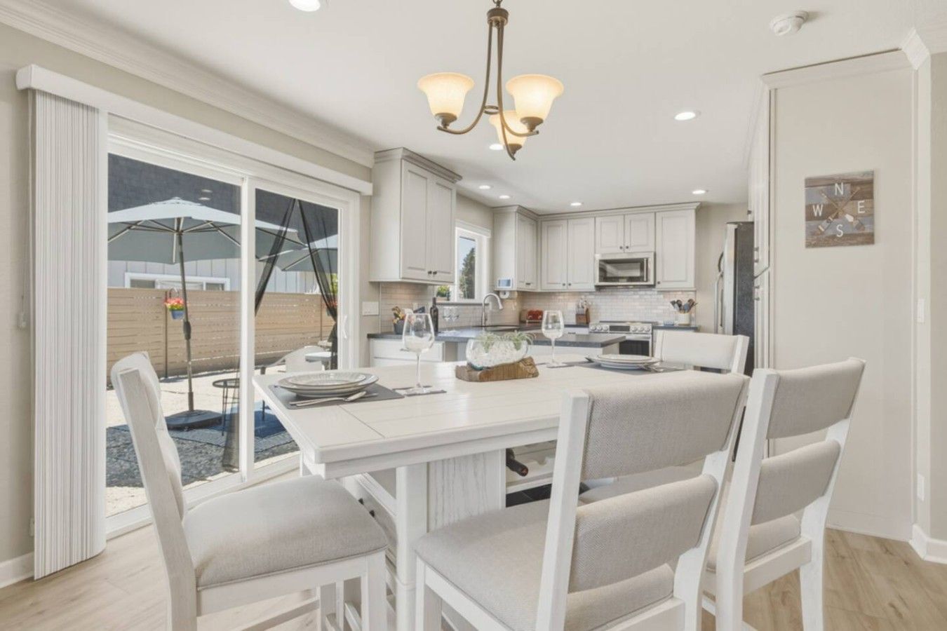A modern kitchen with white cabinetry, a central island, and a dining area with chairs.