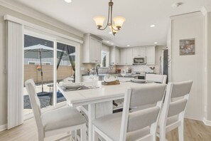 A modern kitchen with white cabinetry, a central island, and a dining area with chairs. - Balboa Blue - Pet friendly in the Tahoe Keys (South Lake Tahoe)
