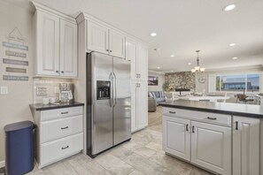 Una cocina moderna con armarios blancos, un refrigerador de acero inoxidable y una pared de acento de piedra.