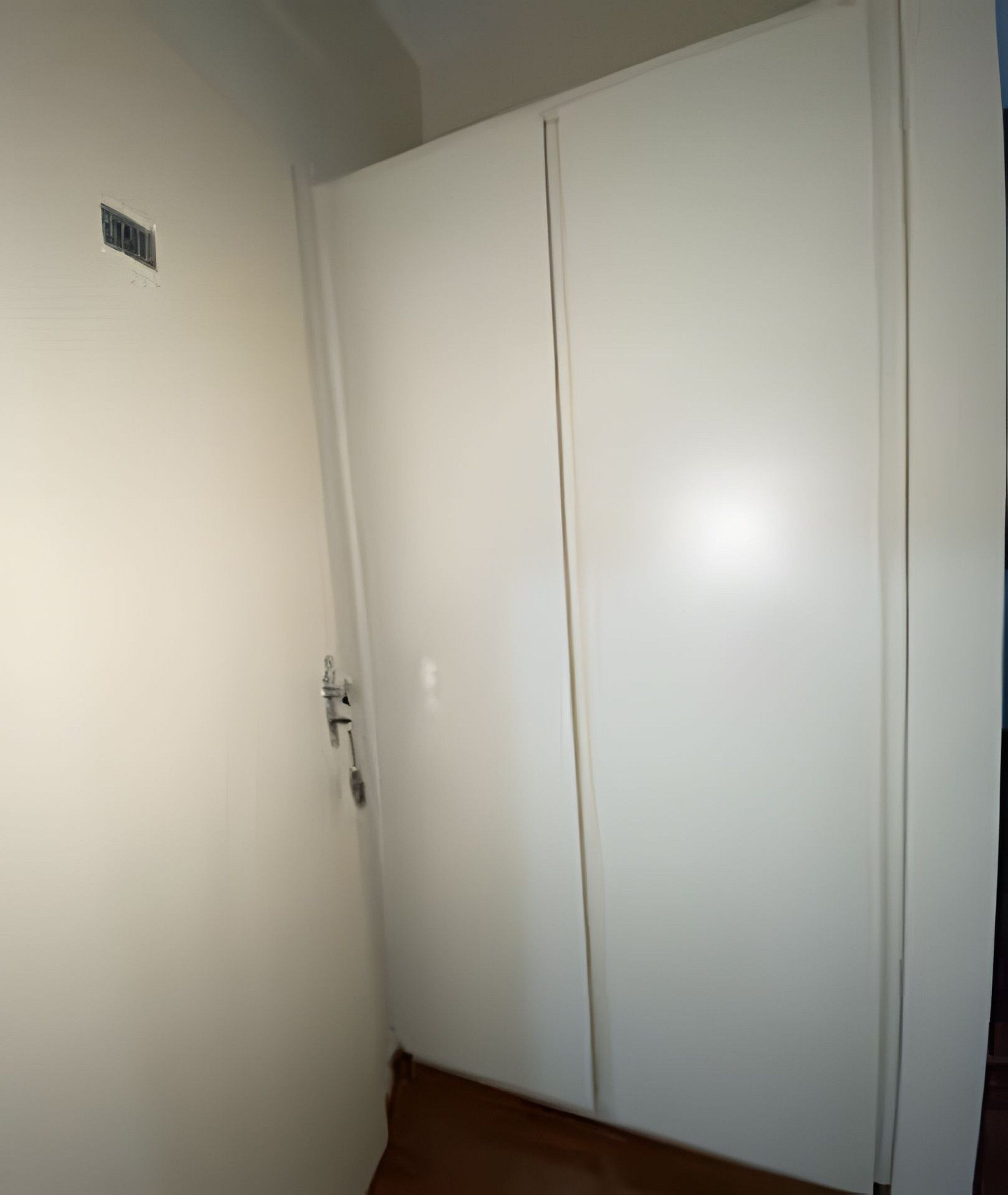 Una puerta blanca cerrada con manija y un pequeño respiradero arriba.