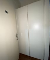 Una puerta blanca cerrada con manija y un pequeño respiradero arriba.