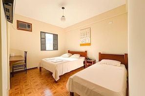 A hotel room with two beds, a desk, a chair, a window with blinds, and a wall-mounted artwork. - LN FLATS & SUÌTES (Uberlândia)