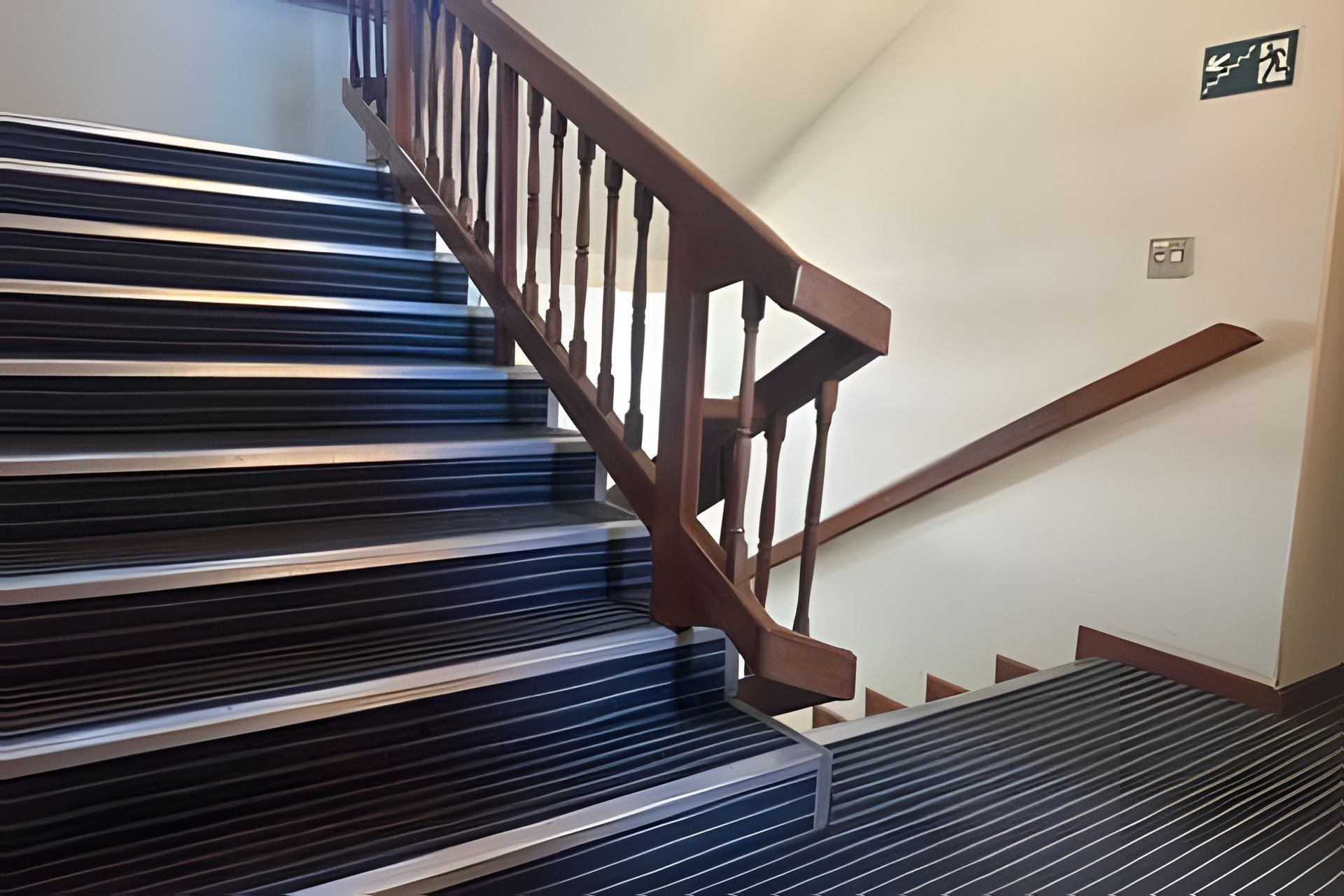 Una escalera con barandillas de madera y un pasamanos de metal.