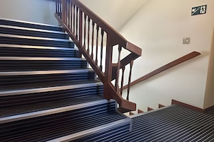 Una escalera con barandillas de madera y un pasamanos de metal.