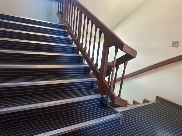 Una escalera de madera con barandilla y pasamanos de metal.