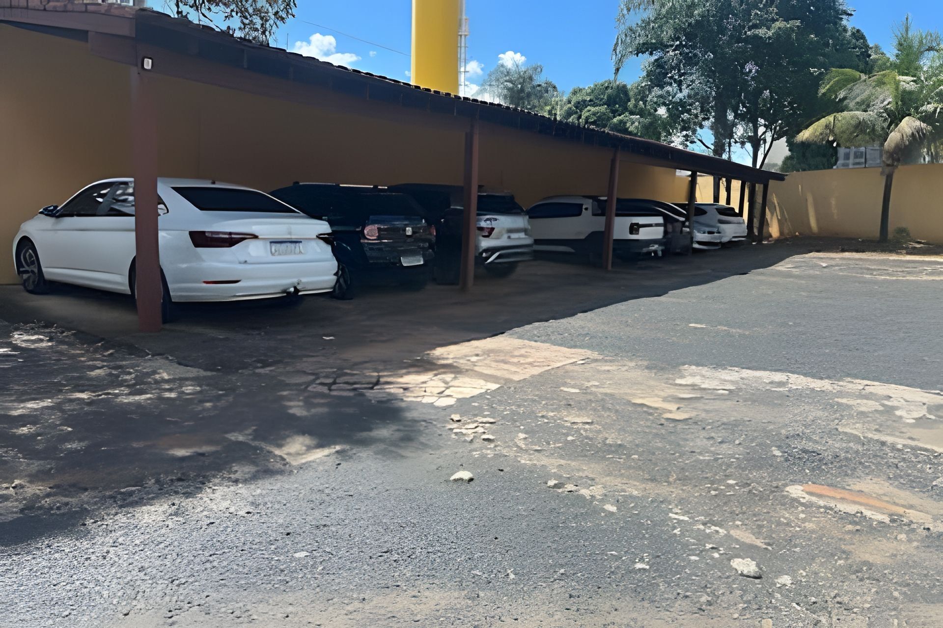 Un área de estacionamiento con varios autos estacionados bajo una estructura techada.
