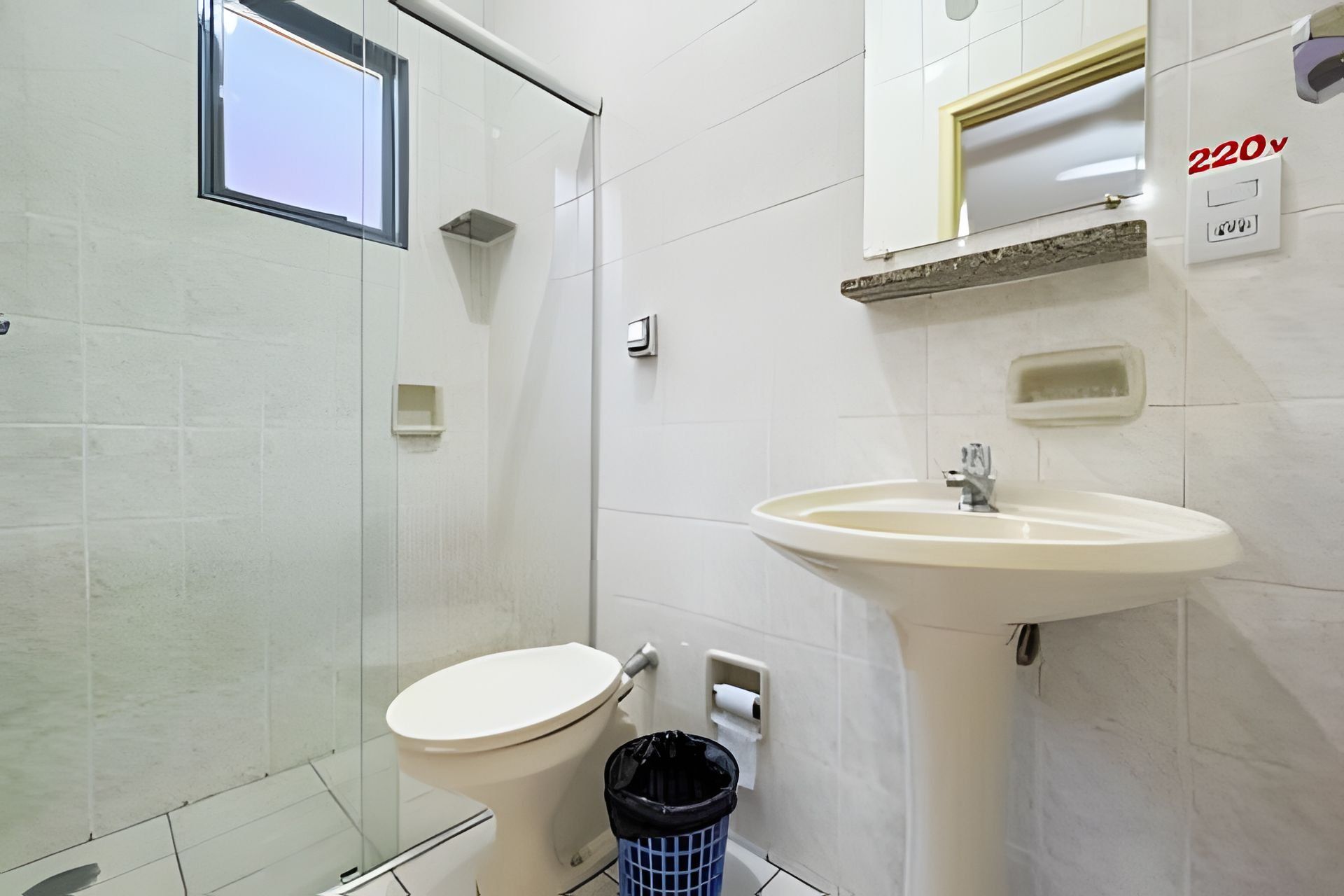 Un bagno con il water, un lavandino e un cestino.