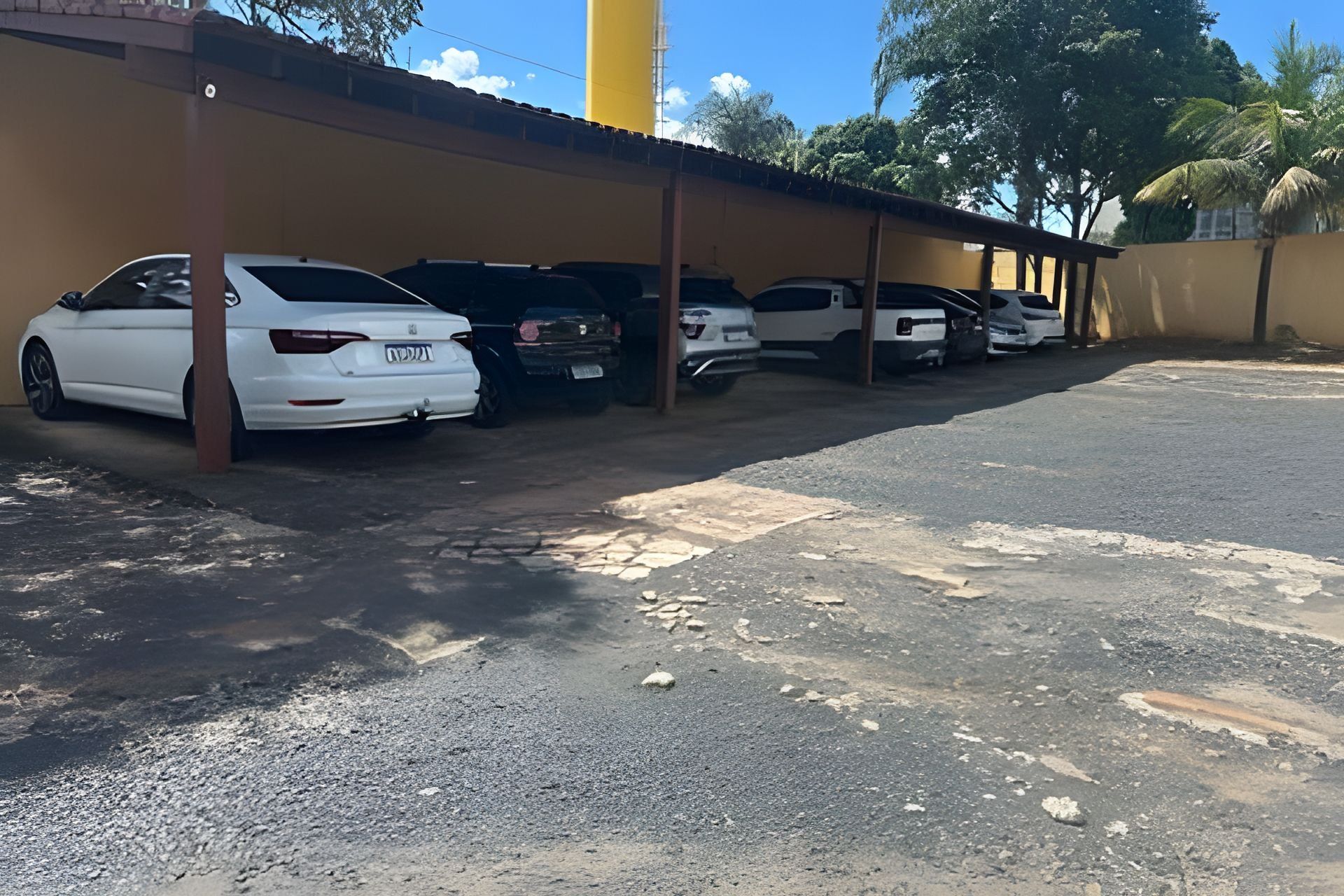 Área de estacionamento com vários carros estacionados sob uma cobertura.