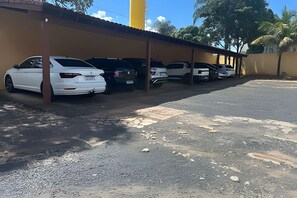 A parking area with multiple cars parked under a covered structure. - LN FLATS & SUÌTES (Uberlândia)