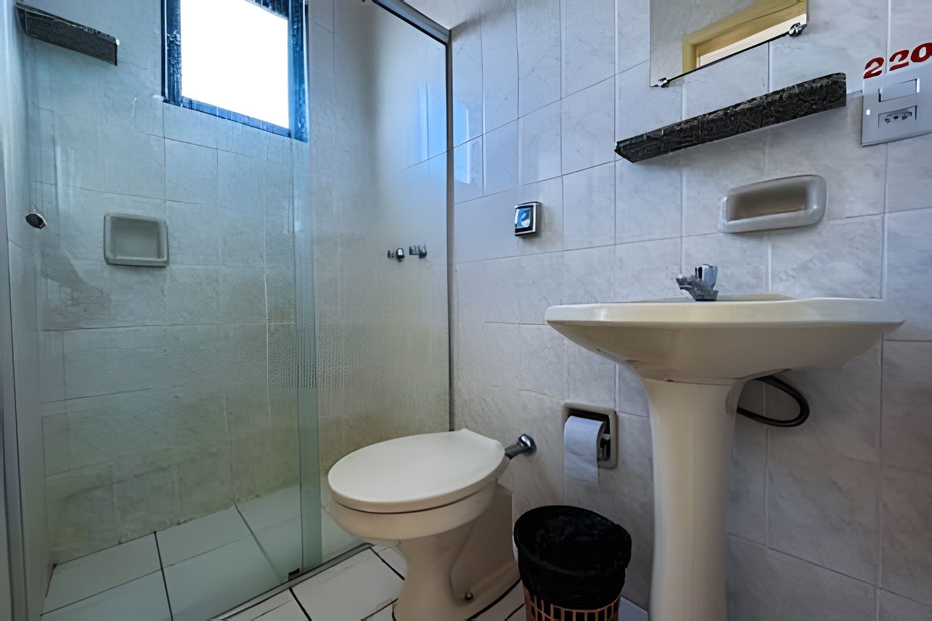 Un baño con inodoro, lavabo y una pequeña ventana.