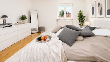 Un dormitorio con cama, mesita de noche, lámpara, espejo y ventana con vistas.