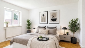 A modern bedroom with a bed, bedside tables, a radiator, a window, and two framed artworks on the wall. - 1OG M schöne Wohnung 10 min von Salzburg (Freilassing)