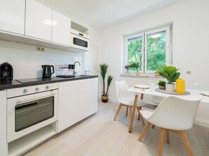 Ett modernt kök med vita skåp, en inbyggd ugn och en matplats med bord och stolar.